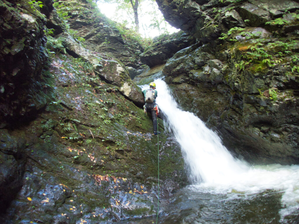 Climber ascending small waterfall in Suginomorisawa Samata stream climbing route