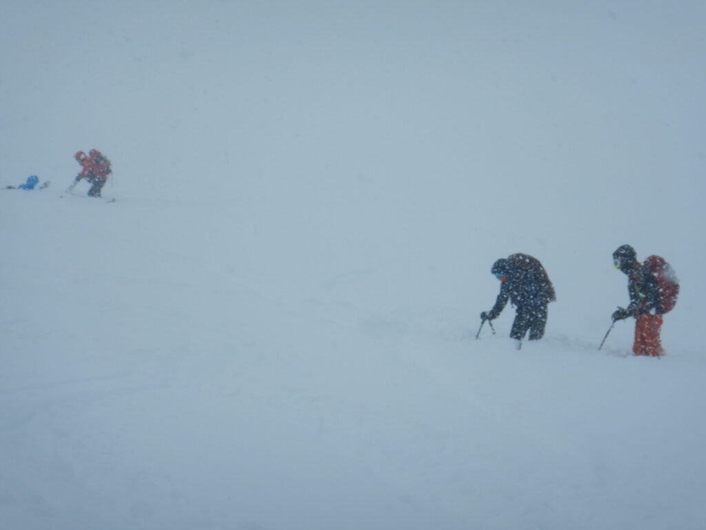 Ski mountaineers on windswept ridge of Mitsuishi-yama in whiteout conditions with reduced visibility