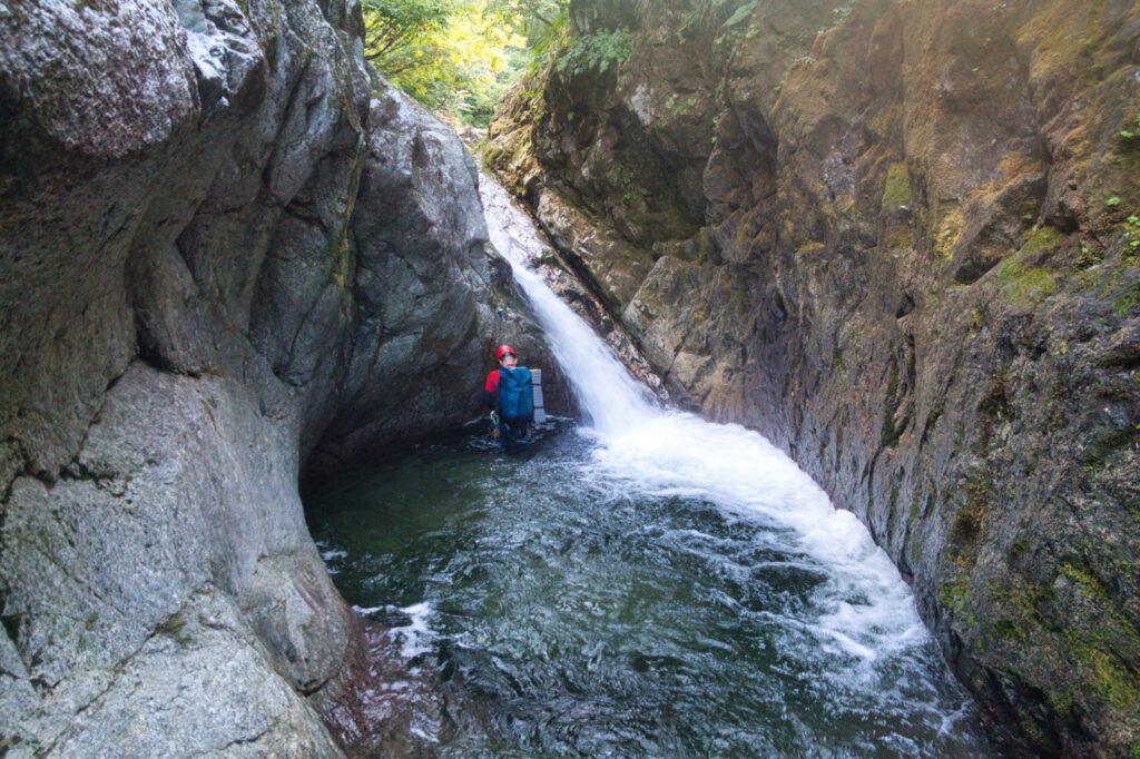 Climber ascending granite waterfall right wall, Nanatakisawa stream climbing route