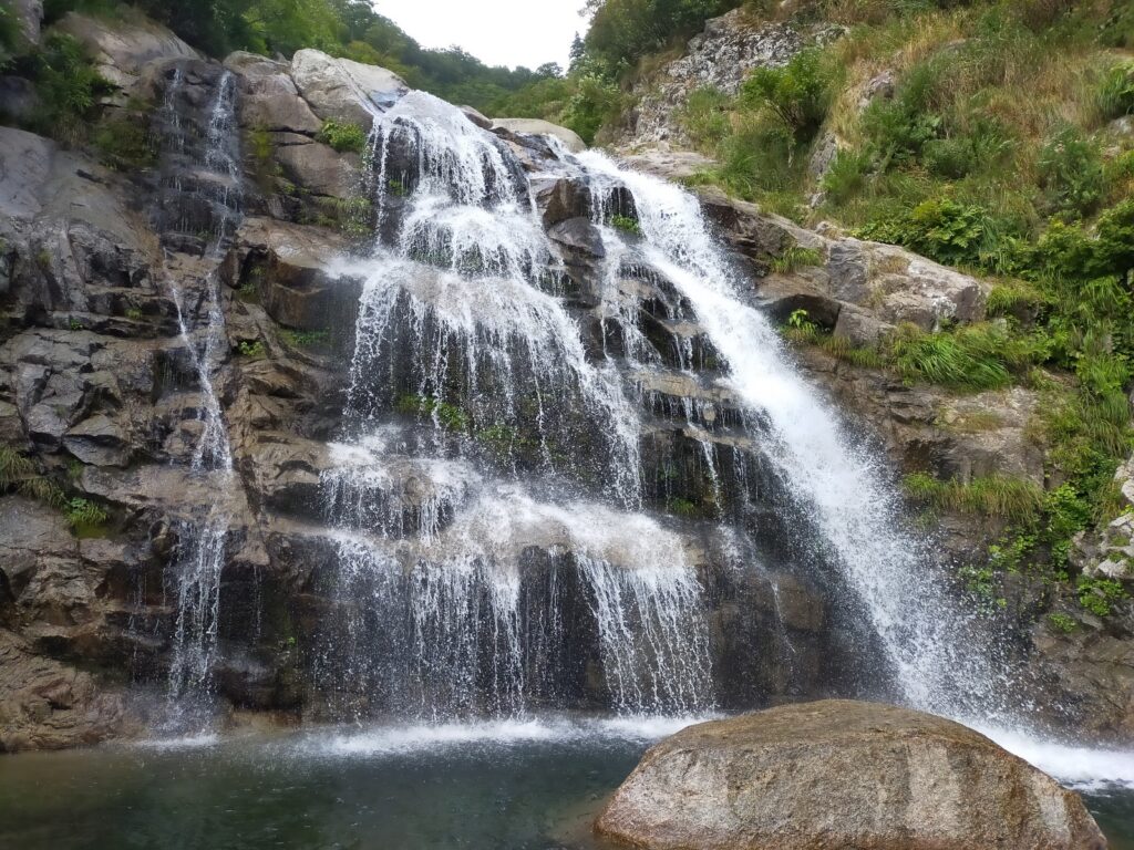 Climber on granite waterfall with rope belay, Nanatakisawa technical climbing Japan