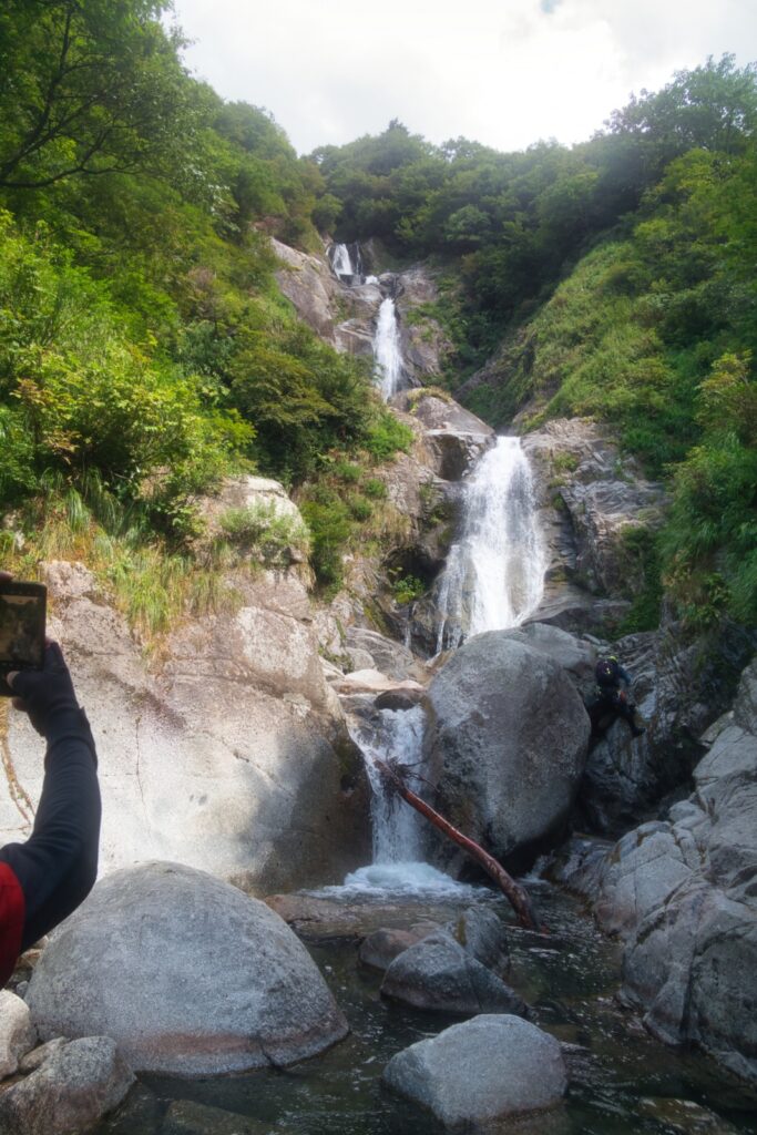 Climber on rope ascending Seven Falls waterfall chain, Nanatakisawa Japan