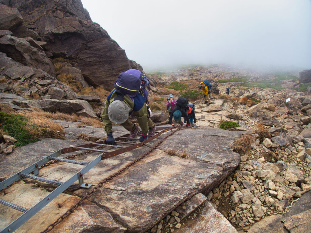 Steel ladder section on serpentine rock wall Mt. Hayachine climbing route