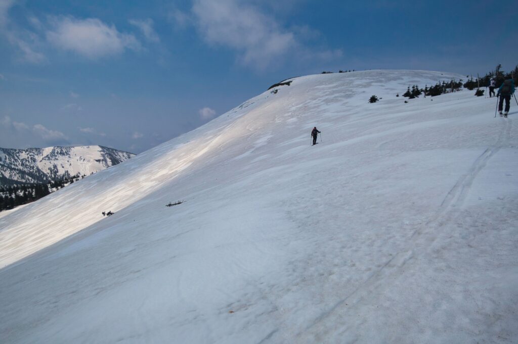 Ski touring group making multiple descents on Yokodake north face in Southern Hakkoda Mountains