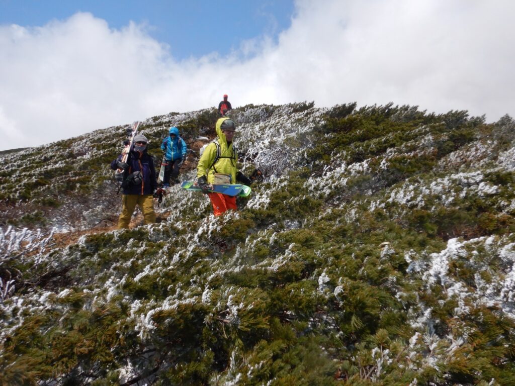 Skiers preparing to descend steep southeast face of Mt. Takadaodake with view down steep slope