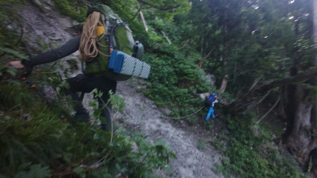Climbers crossing knee-deep Shirahagi River with mountain gear on approach to Mt. Tsurugi Ikenotan Glacier