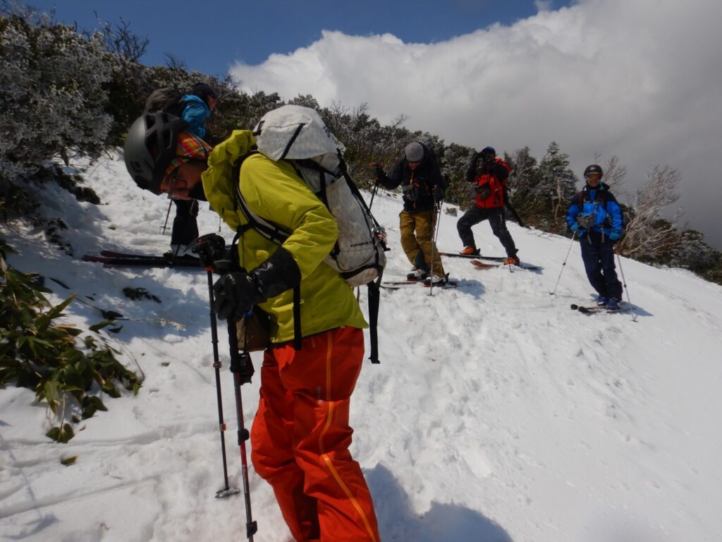 Skier mounting skis and preparing equipment before Mt. Takadaodake southeast face descent