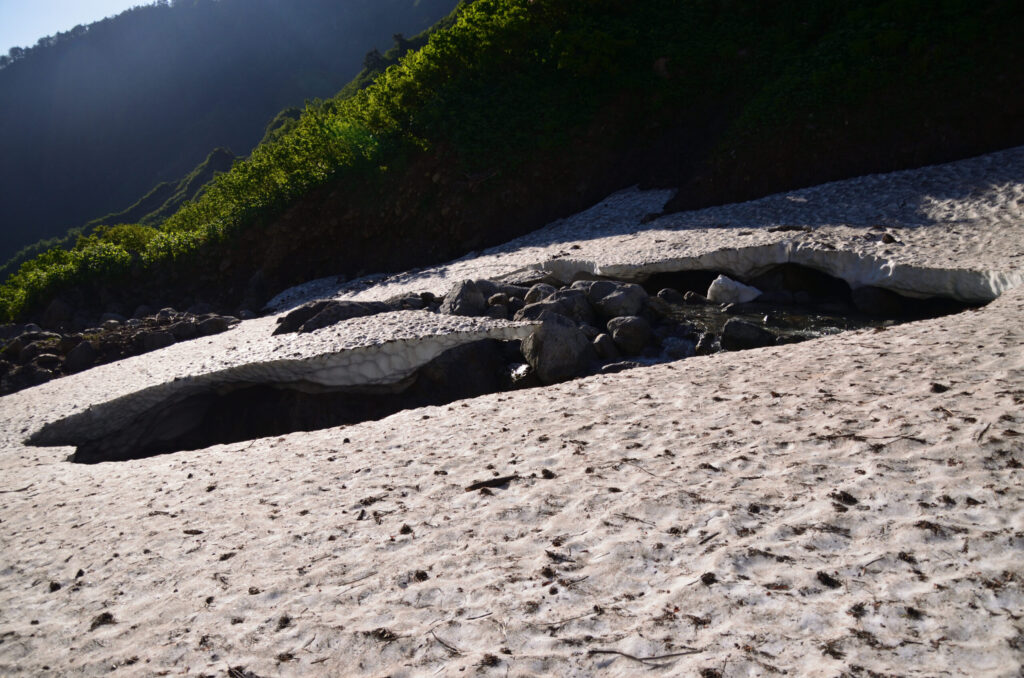 Climber ascending lower section of Ishikorobi snowfield with crampons and ice axe