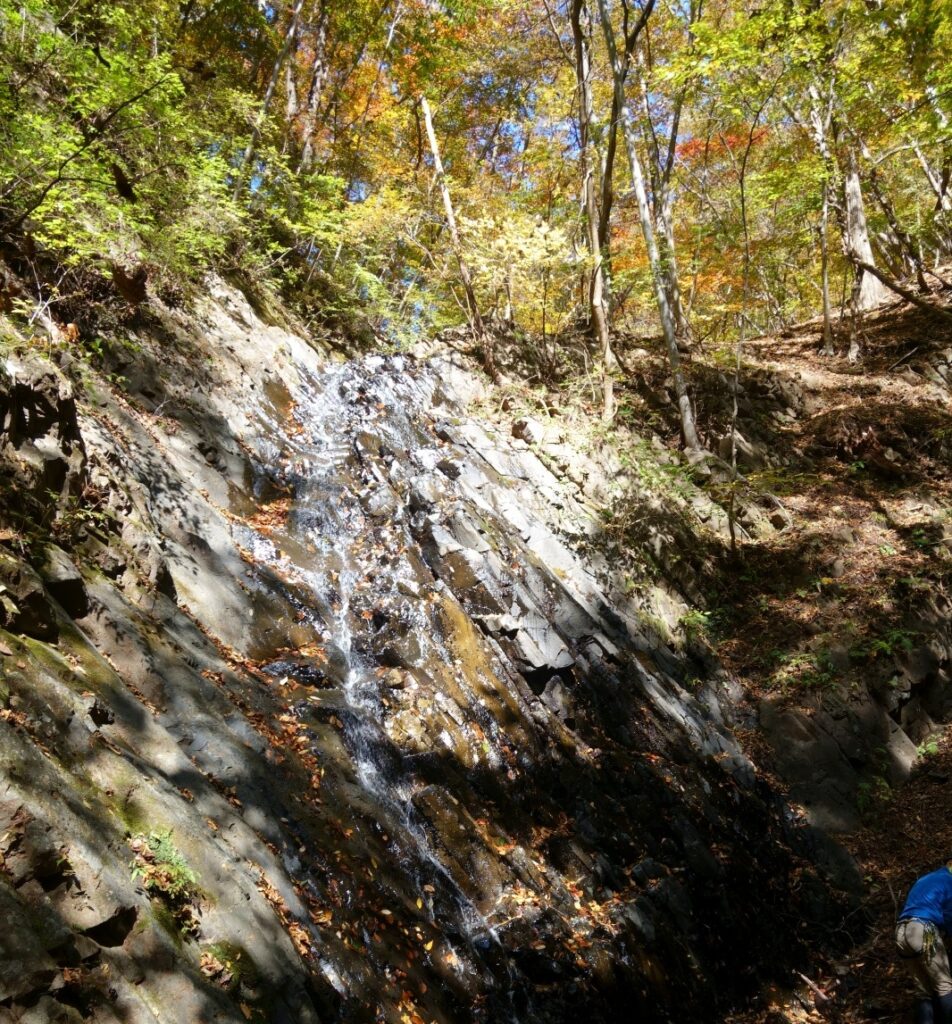 Climber ascending 8-meter columnar basalt waterfall, first crux section, Yakyusawa Right Fork, Japan