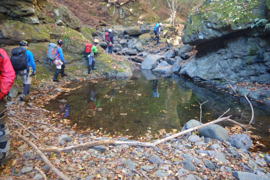 Climbers wading through stream with autumn foliage, Yakyusawa Right Fork, Ura-Myogi, Japan