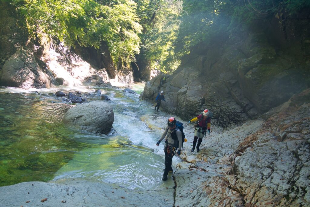 Wading and crossing Kitanomata-zawa through goro boulder field, dense beech forest above, Hachimantai Japan