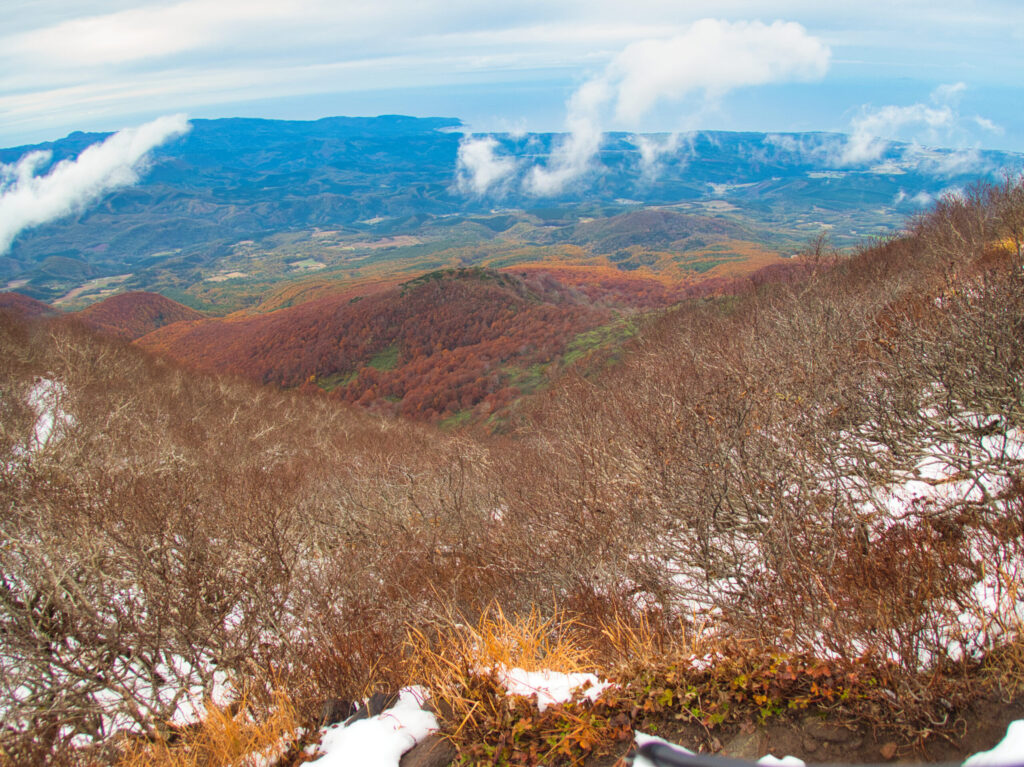 Guided climbing group carefully ascending snow-covered rocky terrain on Mt. Iwaki-san, Japan