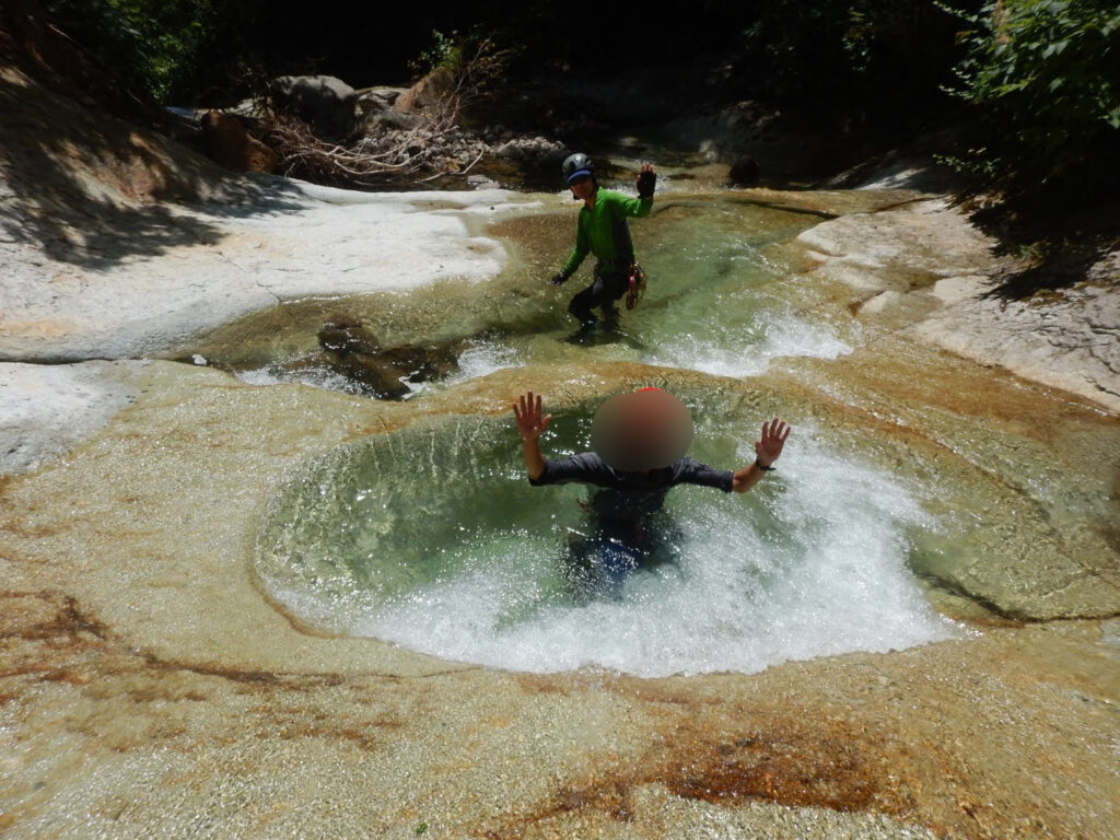 Climbers playing in plunge pool kama of Akedori-zawa stream during descent, Hachimantai Japanｃ