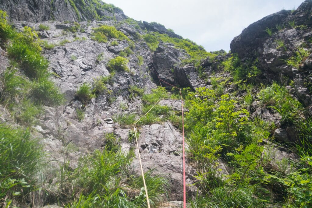  "Climber in wet granite couloir with heavy piton protection, technical chimney section"