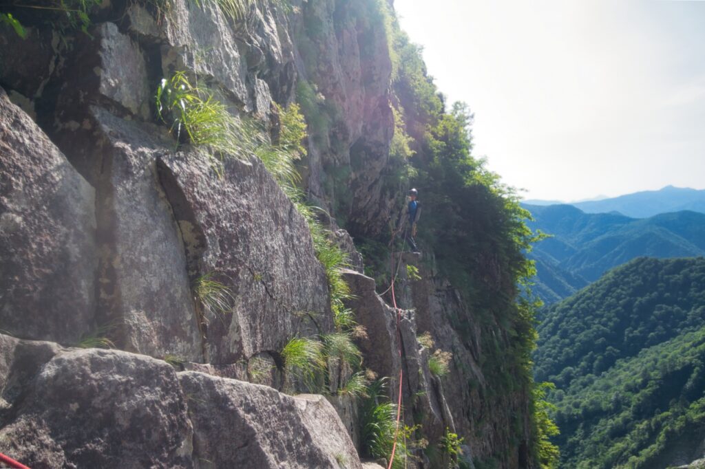 "Climber on wet granite traverse, first pitch of Central Buttress, Ichinokura-sawa"